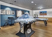 Thumbnail 5 of 14 - Game room with dome hockey and air hockey tables at Grand Gateway Apartments, St Cloud, MN 56301