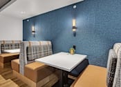 Thumbnail 4 of 14 - Dining area with booth seating and blue accent wall at Grand Gateway Apartments, St Cloud, MN
