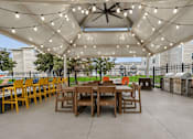Thumbnail 21 of 40 - Covered outdoor dining area with string lights at Prosper West Apartments, Waite Park, MN