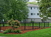 Thumbnail 10 of 25 - Black fence with landscaping and mulch bed at Regency Park Apartments, St Cloud, 56304