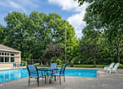 Thumbnail 12 of 25 - Outdoor pool with patio seating and lush trees at Regency Park Apartments, Minnesota, 56304