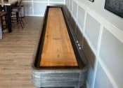 Thumbnail 48 of 56 - a shuffleboard table in a room with a clock on the wall