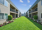 Thumbnail 2 of 10 - A long row of apartment buildings with green lawns in between.