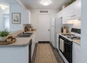 Thumbnail 13 of 16 - A kitchen with a stove, sink, and refrigerator.