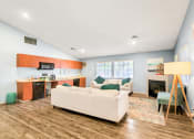 Thumbnail 10 of 13 - a living room with a couch a chair and a kitchen with a stove and microwave