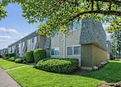 Thumbnail 3 of 10 - A row of houses with green bushes in front.