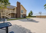 Thumbnail 2 of 14 - A basketball court is located in front of a large house.