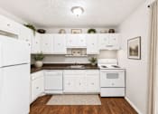 Thumbnail 10 of 13 - Compact kitchen with white appliances and wood countertops at Stratford Arms Apartments, Georgia