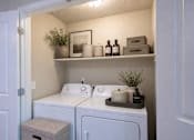 Thumbnail 20 of 20 - Laundry room with washer and dryer and storage shelf at The Ellison Apartments, Layton, 84041