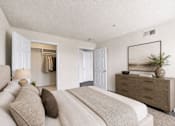 Thumbnail 16 of 17 - A bedroom with a large bed and a dresser with a mirror above it.