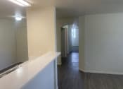 Thumbnail 2 of 13 - a kitchen and living room with white walls and wood flooring