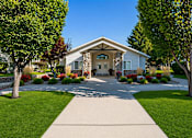 Thumbnail 1 of 10 - A house with a stone facade is surrounded by a well-kept lawn and trees.