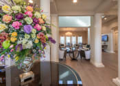 Thumbnail 6 of 26 - A large floral arrangement sits on a table in a spacious room.