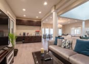 Thumbnail 7 of 26 - A modern living room with a large couch and a kitchen area.