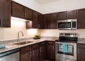 Thumbnail 4 of 26 - A kitchen with brown cabinets and a stainless steel oven.