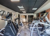 Thumbnail 21 of 24 - A gym with treadmills and elliptical machines.