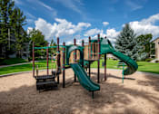 Thumbnail 4 of 7 - A playground with a green slide and a brown sandbox.