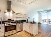 Thumbnail 29 of 36 - A modern kitchen with a stainless steel range hood and black countertops.