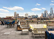 Thumbnail 14 of 36 - A rooftop patio with a table and chairs overlooking a city skyline.