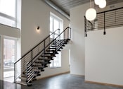 Thumbnail 33 of 36 - A staircase with a metal railing and a light hanging from the ceiling.