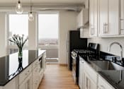 Thumbnail 25 of 36 - A modern kitchen with black countertops and white cabinets.
