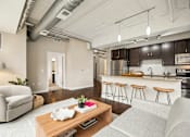 Thumbnail 1 of 43 - A modern living room with a kitchen in the background.