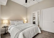Thumbnail 14 of 43 - A bedroom with a bed, two lamps, and a ceiling fan.