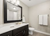 Thumbnail 19 of 43 - A bathroom with a white counter top and a white toilet.