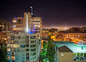Thumbnail 30 of 40 - A tall building with a flag on top is lit up at night.
