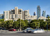 Thumbnail 8 of 40 - A city street with cars and buildings in the background.