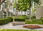 Thumbnail 15 of 40 - A well-manicured garden with a bench and a flower bed in the foreground.