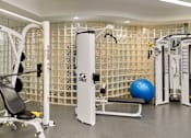 Thumbnail 28 of 40 - A gym with a variety of equipment including a leg press machine, a bench, and a ball.