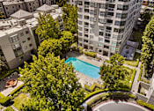 Thumbnail 13 of 40 - A swimming pool surrounded by trees and buildings.