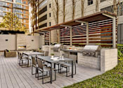Thumbnail 14 of 40 - A patio with a table and chairs and a grill.
