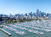 Thumbnail 56 of 95 - A marina filled with lots of boats in front of a city skyline.