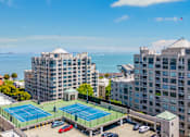 Thumbnail 6 of 95 - A tennis court is located between two buildings.