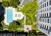Thumbnail 7 of 95 - A swimming pool is surrounded by trees and grass in a courtyard.
