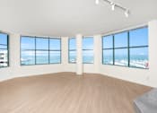 Thumbnail 5 of 95 - A large empty room with wooden floors and large windows overlooking a city.