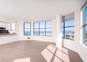 Thumbnail 2 of 95 - A spacious room with wooden floors and large windows overlooking a cityscape.