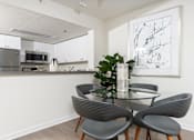 Thumbnail 69 of 95 - A modern kitchen with a glass dining table and grey chairs.