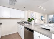 Thumbnail 70 of 95 - A kitchen with white cabinets and a grey countertop.