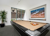 Thumbnail 39 of 95 - A pool table with a brown cloth and a television on the wall.
