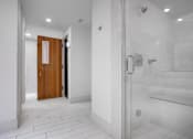 Thumbnail 76 of 95 - A white tiled bathroom with a wooden door.