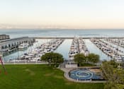 Thumbnail 81 of 95 - A marina with boats docked in the water and a circular fountain in the foreground.