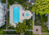 Thumbnail 82 of 95 - An aerial view of a pool surrounded by a building and trees.