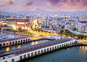 Thumbnail 86 of 95 - A cityscape at dusk with a marina in the foreground.