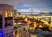 Thumbnail 92 of 95 - A cityscape at night with a bridge in the background.