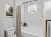 Thumbnail 8 of 54 - a bathroom with a white toilet next to a bathtub with a shower at Two Addison Place Apartments , Pooler, GA