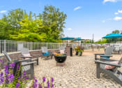 Thumbnail 16 of 30 - an outdoor patio with tables chairs and umbrellas and a fire pit at Sycamore at Tyvola, Charlotte, NC, 28217
