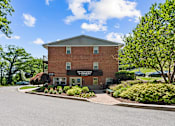 Thumbnail 19 of 20 - A building with a sign that reads "Kingdom Hall" sits in front of a tree and bushes.